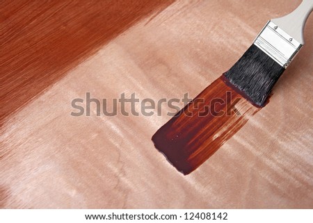 Paintbrush and fresh paint on wooden surface.