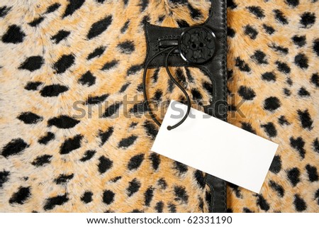 Blank label or price tag attached to a button of stylish leopard clothing.