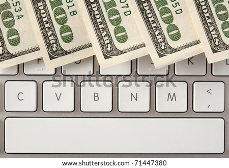 US hundred dollar bills on white computer keyboard with spacebar.