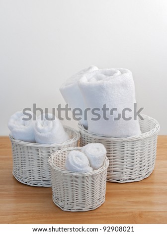 Clean towels in white wicker baskets, on a wooden surface.