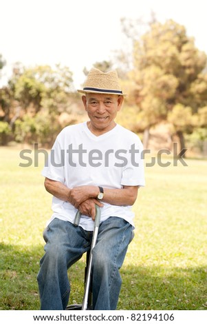 old man sitting on chair  with walking stick in a park