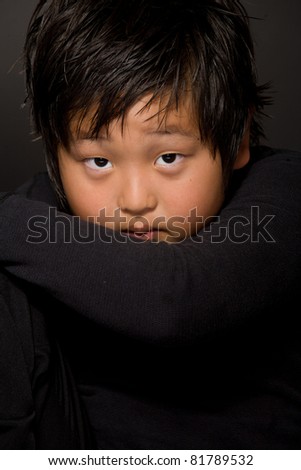 portrait of young boy sitting on a  chair  against black background