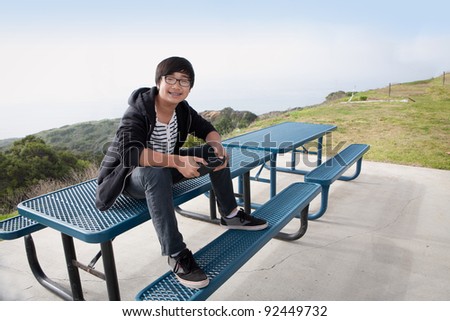 young boy sitting on picnic table with tablet PC smiling