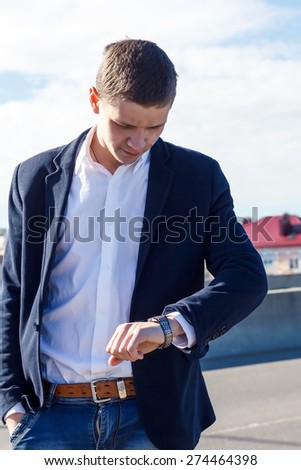 young man looking at his watch on the street