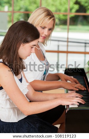 Young girl taking piano lessons from a teacher