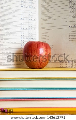 Stack of books and apple with a vintage report card