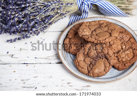 Plate of chocolate cookies with bunch of lavender on a rustic wooden table with copyspace