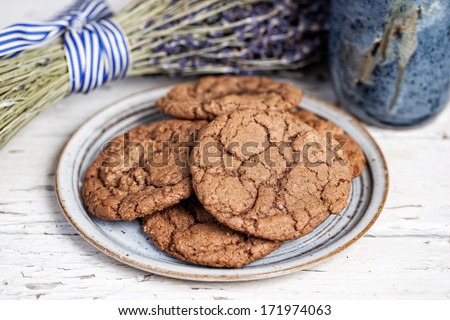 Plate of chocolate cookes with bunch of lavender on a rustic wooden table