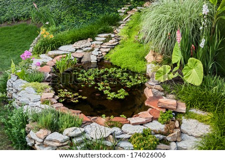 Beautiful Pond In A Backyard Surrounded With Stone During Summer