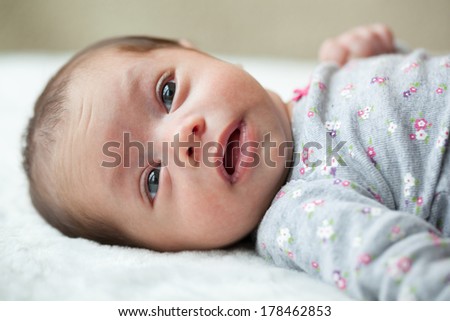 Newborn baby girl 6 weeks old with eyes open laying on a blanket