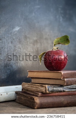 Vintage chalkboard with stack of books and apple on rustic wooden table and vintage filtered effect