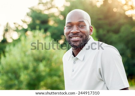 Portrait of a late 20s black man sitting at the park on a summer day with filtered effect