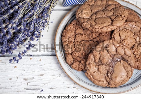 Top view of a plate of chocolate cookies with bunch of lavender on a rustic wooden table with copyspace