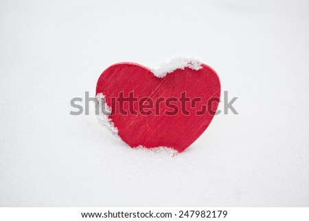 Red painted wooden heart covered in real fresh snow in winter for Valentines Day