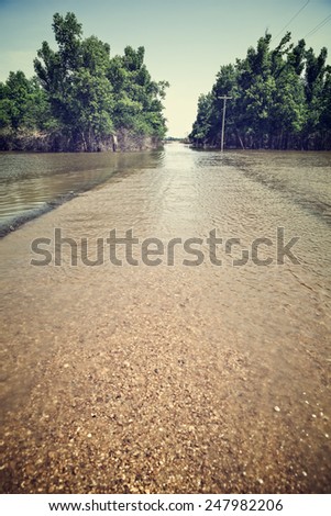 Flooded road in rural America after heavy spring rains with vintage filtered effect