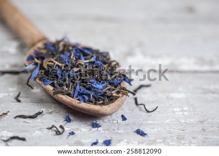 Loose Earl Grey tea leaves on a vintage wooden spoon and table