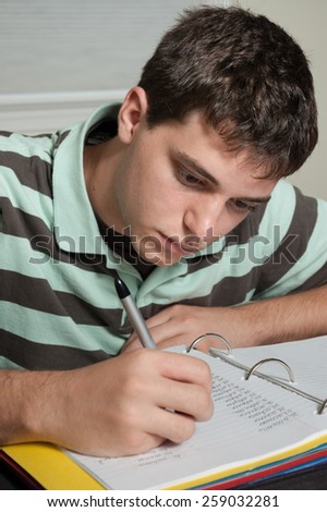 Teen boy high school student doing French foreign language homework in a notebook