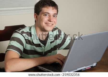 16 year old boy high school student doing homework on a laptop computer