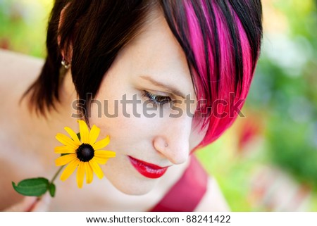 Portrait of an attractive punk woman with pink hair holding flower in the garden