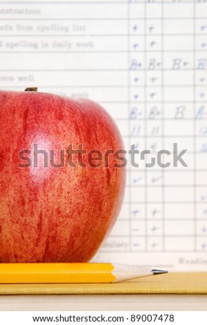Red apple in front of a vintage report card