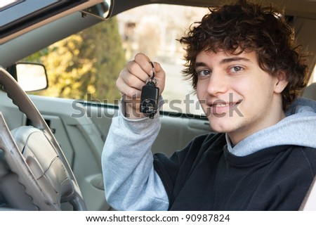 Teenage boy and new driver behind wheel of his car holding keys