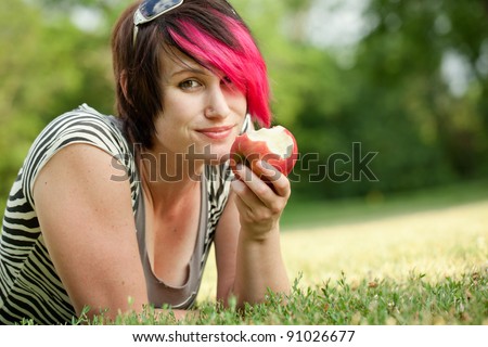 Punk woman eating an apple at the park