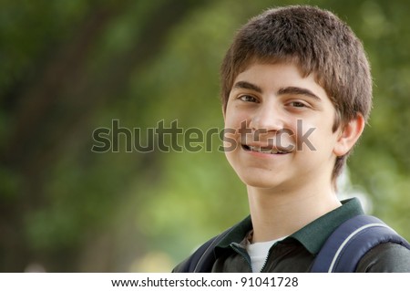 Preteen boy portrait with backpack strap outside under trees