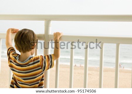 Child looking out at the ocean from a balcony in Virginia Beach