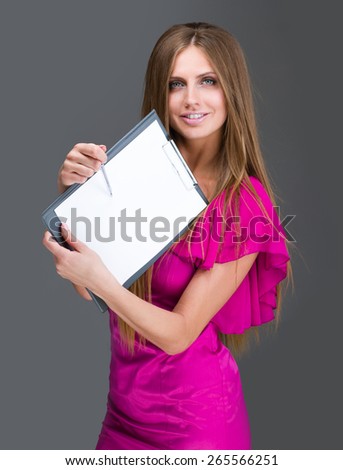 Smiling young business woman showing blank signboard, over gray background