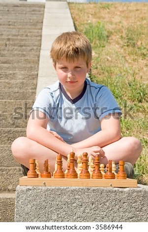 beginning of the game. little boy chess in a summer park