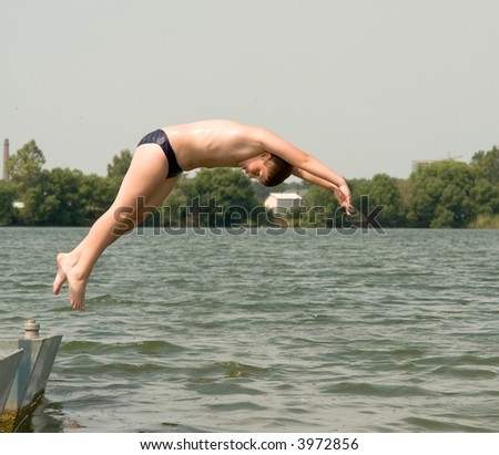 The little boy jumps from a pier in water