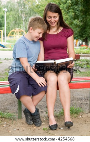Mum and the son reads the book in park