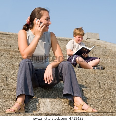 girl with mobile phone on a stone staircase. boy reads book