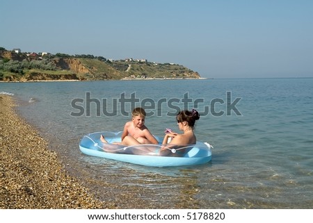 Mum and the son in an inflatable boat on the beach