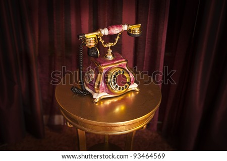 Vintage phone on the table on red curtain background from top corner