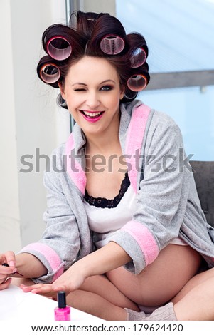 Pregnant woman with hair rollers getting nail treatment