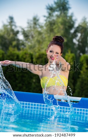 Woman it the garden splashing water from pool