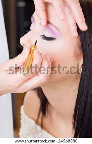 Woman putting on models eye make up