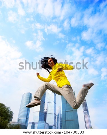business woman in sports clothing jumping on the background of office buildings, metaphor