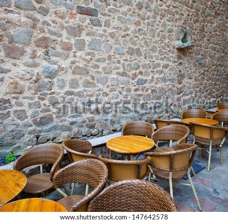tables and wicker chairs in summer cafe near the ancient stone wall