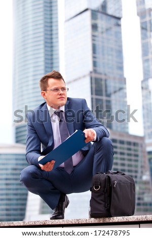 successful businessman on background of office skyscrapers dreams of the future with tablet in hands