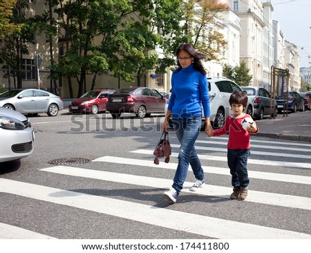 woman with a child going on a pedestrian crossing in the city