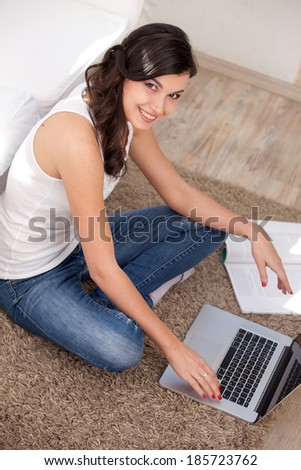 Young woman resting with notebook on floor near sofa, at campus