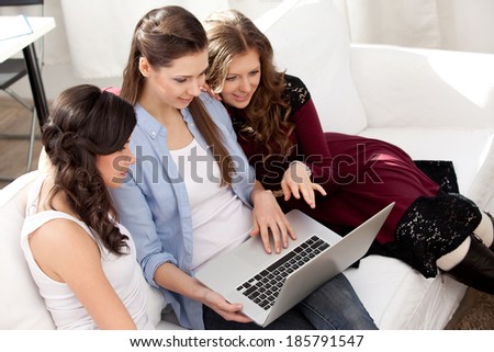 three young  smiling woman resting with notebook on sofa, at campus