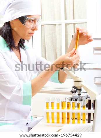 female scientist considering the sample tube in the life science research laboratory: biochemistry, genetics, forensics, microbiology