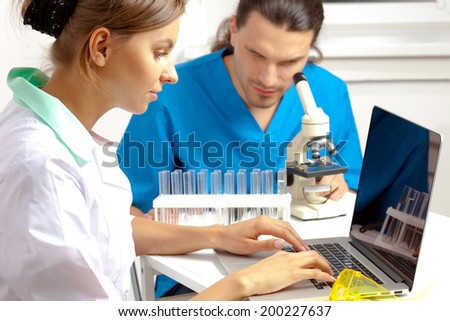 Doctor enters data into the computer, a researcher looking in to microscope on the background