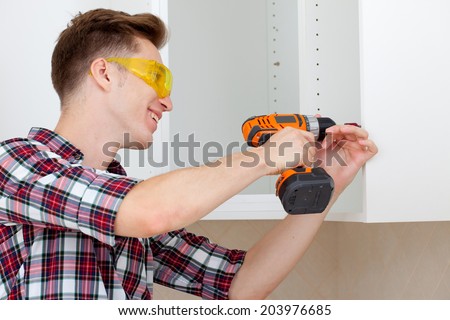 young worker in protective glasses with screwdriver to assemble furniture