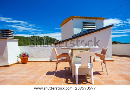 table and chairs on the roof under the open sky on a sunny day