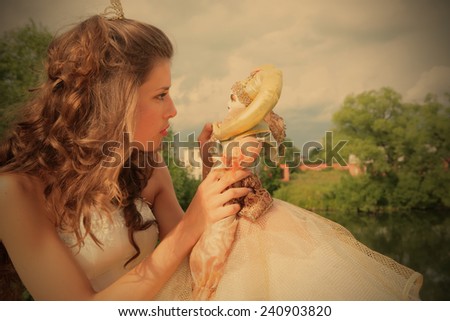 princess in white-golden gown plays with loved doll on background cloudy sky, instagram image style