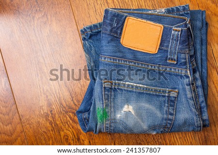 old blue jeans with brown label on the belt smeared with green paint and a pocket full of holes, which were stored for a long time a mobile phone